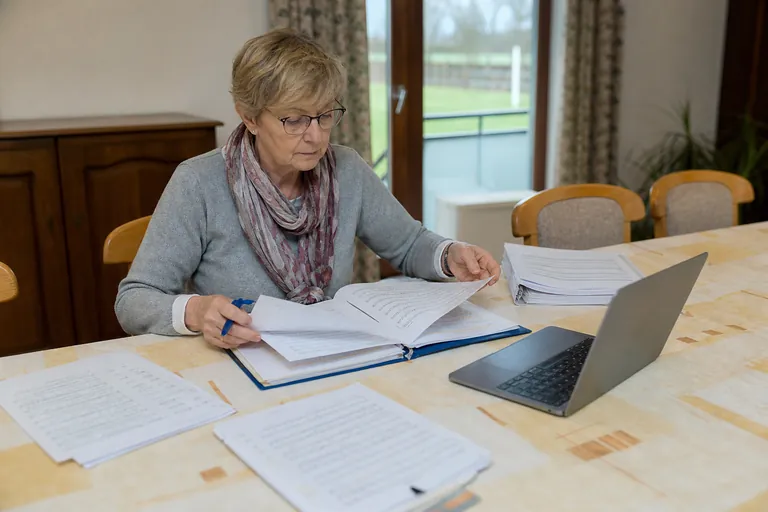 Notenwartin vergleicht gedruckte Chornoten mit Unterlagen auf einem Tisch im Gemeindehaus.
