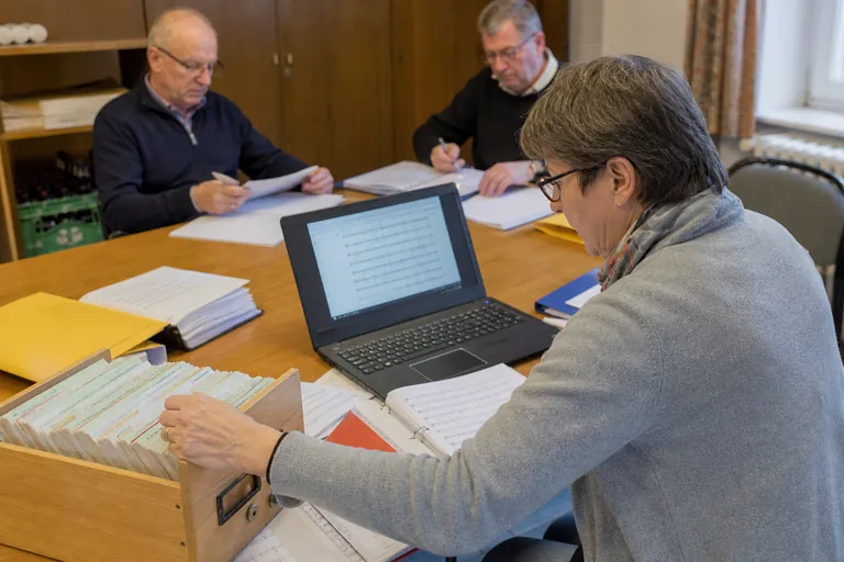 Karteikasten, Laptop mit Tabellenansicht und Notenmappen als Wege der Notenverwaltung.