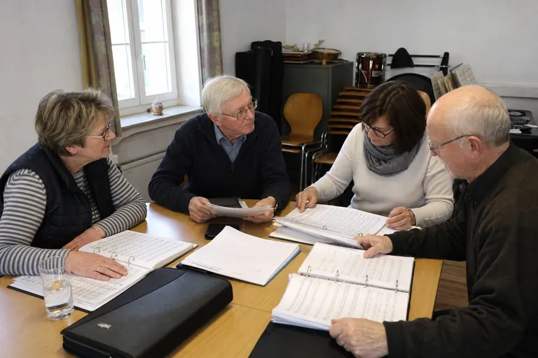 Vorstand, Chorleitung und Notenwartin besprechen Unterlagen und Notenmappen.